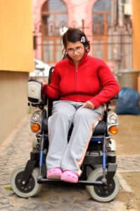 young woman sitting in a wheelchair on a street