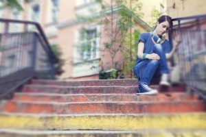 Unhappy teenage girl sitting outside on steps