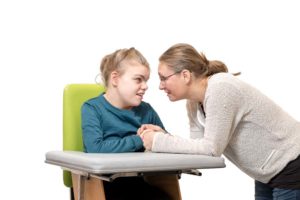 woman holding hand of girl with disability and looking at each other closely