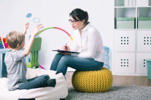 young woman holding clipboard speaking to a small boy