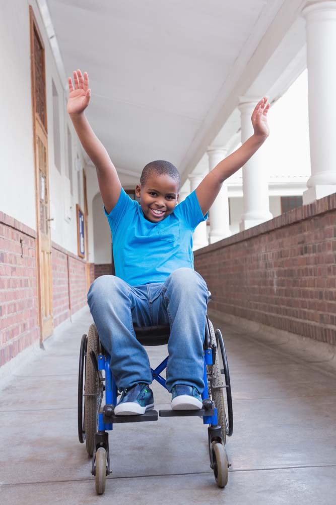 young boy in a wheelchair waving his arms in the air