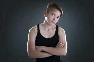 young person with short hair and arms crossed