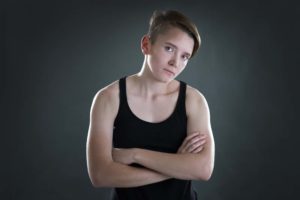 Young person with short hair and arms crossed