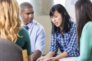 Young Asian woman talks in group of people.